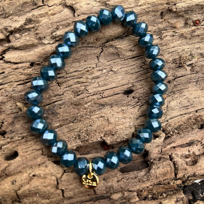 Perlenarmband für Damen mit facettierten Kristallperlen in Petroliris (ca. 8 mm) und elastischem Band. Eleganter Damenschmuck mit original Biba-Anhänger