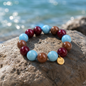Perlenarmband mit großen 18 mm Perlen in Bordeaux, Cognac und Hellblau, glänzend auf einem natürlichen Untergrund arrangiert.