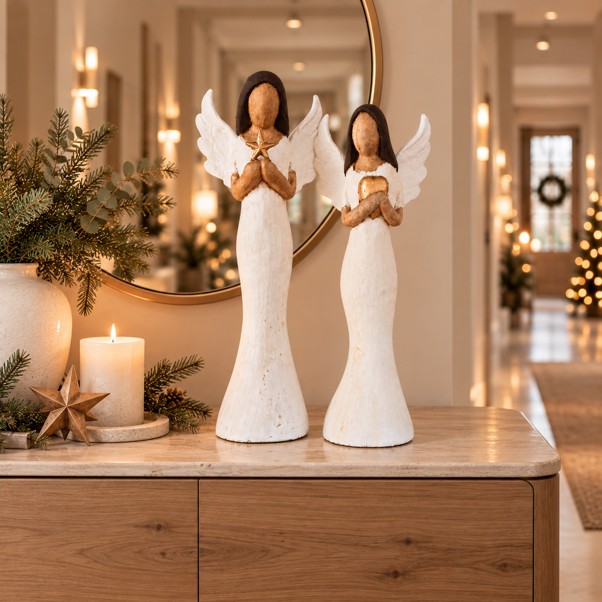 Zwei moderne, große Weihnachtsengel-Figuren in weiß goldener Holzoptik stehend als Weihnachtsdekoration im Flur auf einer Kommode.