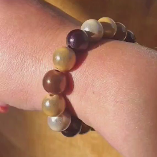 Braunes und mehrfarbiges Perlenarmband mit schimmernden Perlen in warmen Braun-, Beige- und Naturtönen, am Handgelenk getragen und in der Hand präsentiert.