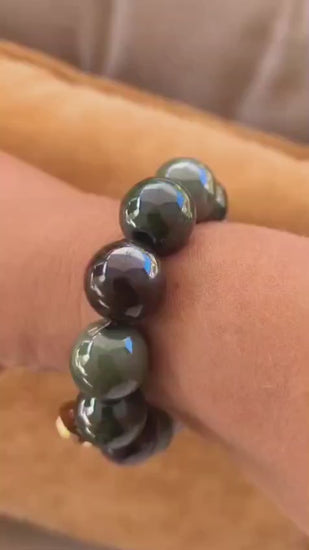 Perlenarmband mit 18 mm großen glänzenden Perlen in harmonischen Herbstfarben, stilvoll präsentiert am Handgelenk